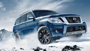 light blue Nissan Armada with chrome grill driving in the snow